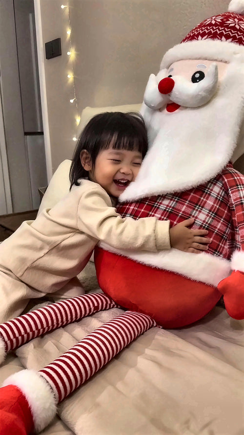 Toddler hugging the giant Cuddle Santa